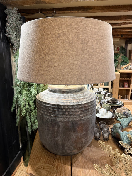 Table lamp with textured base and beige lampshade on a wooden table.