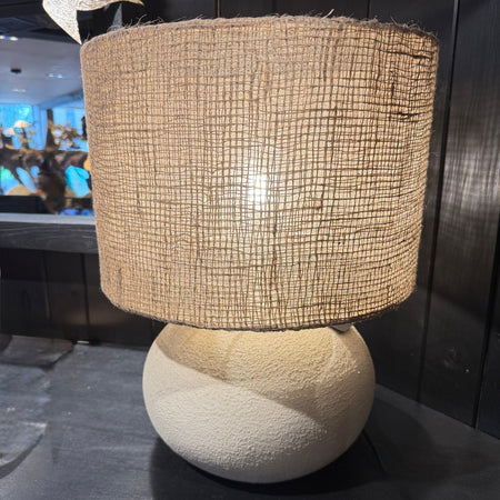 Stone and cement lamp base with jute shade on black shelf