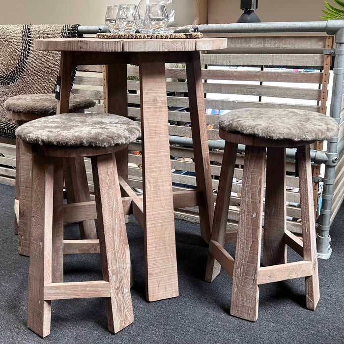 Teak bar stools by Gommaire with cushioned seats around a wooden table in a showroom setting.