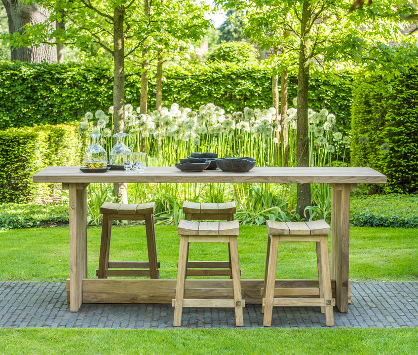 Wooden outdoor dining table with Gommaire Alexi Bar stools in a garden setting