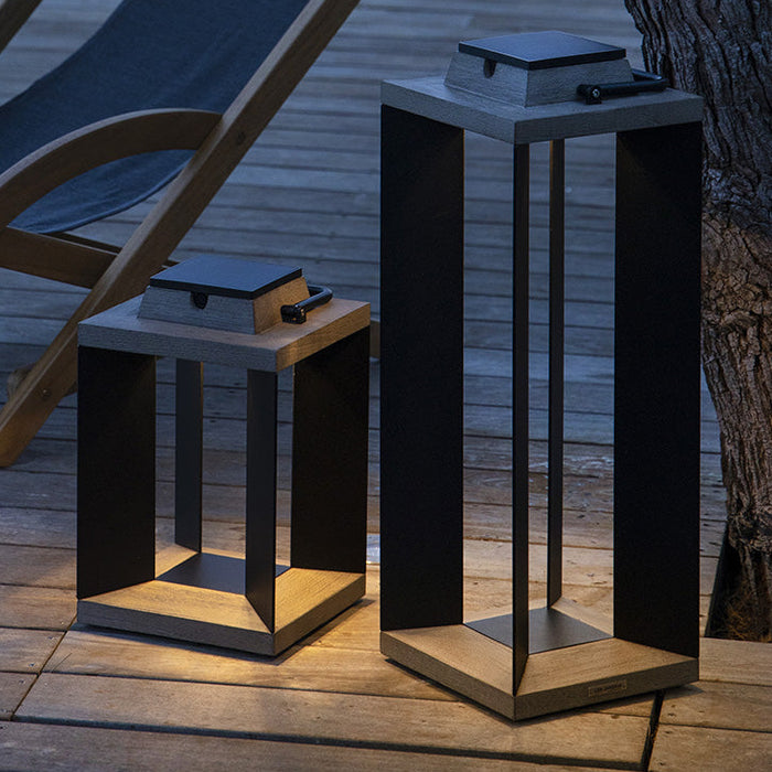 Wooden lounge chair on a wooden deck with two modern outdoor solar lamps.