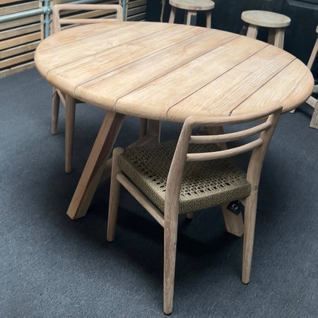 Round wooden table with chairs on a gray floor