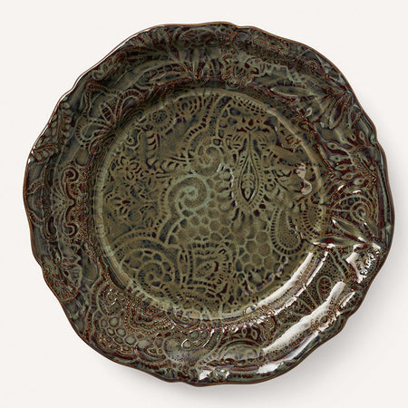 A decorative brown ceramic plate with an ornate floral pattern.
