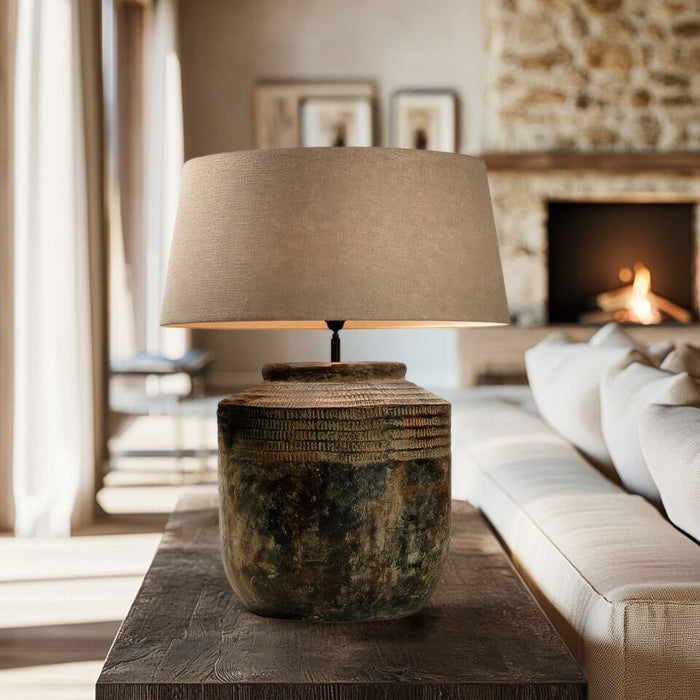 Table lamp with a textured base on a wooden table in a cozy living room.