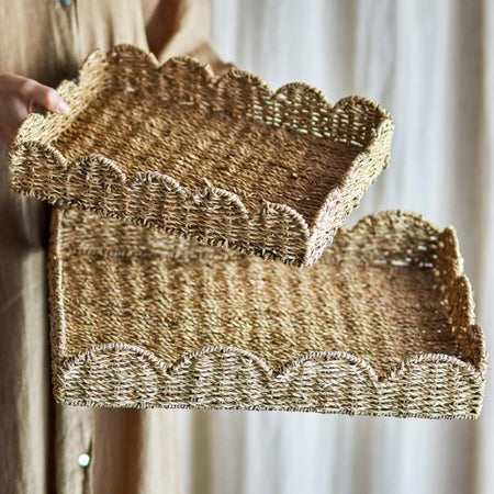 Woven basket with scalloped edges held by a person against a neutral background
