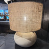 Stone and cement lamp base with jute shade on black shelf