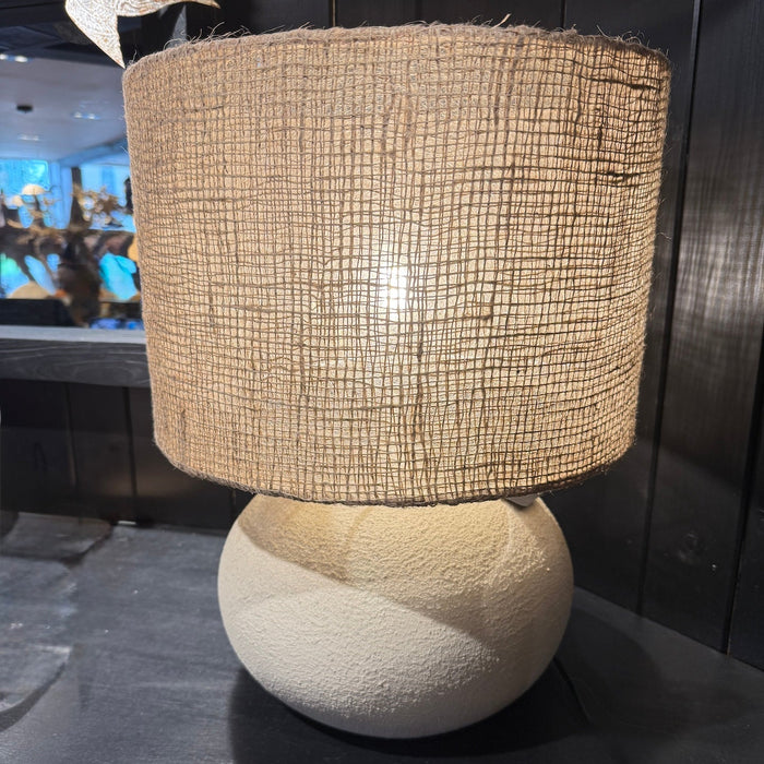 Stone and cement lamp base with jute shade on black shelf