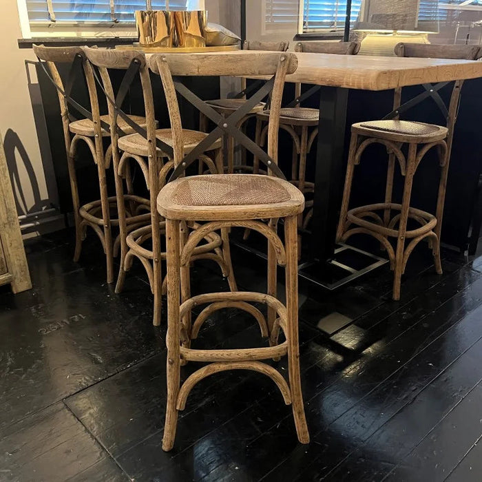 Set of wooden bar stools around a high table in a room with dark flooring.