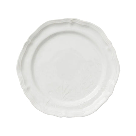 A white matte dinner plate with a wavy edge on a plain background.