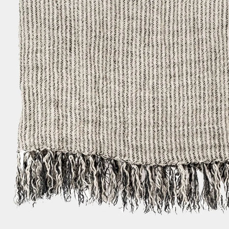 Textured linen throw with fringes on a light gray background