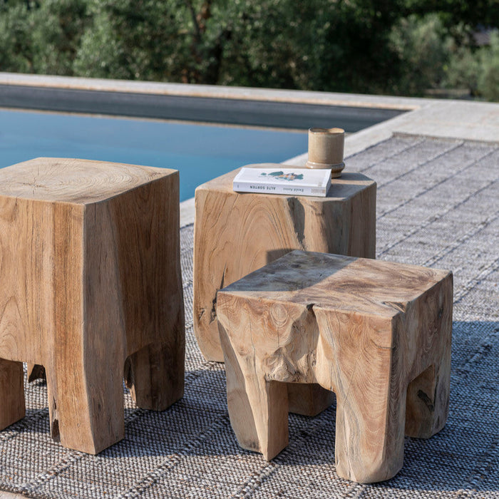 Gommaire teak Doblo side tables by a poolside with a book and cup on top