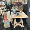 Teak bistro table with crossed leg design in showroom setting