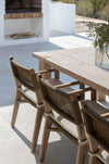Outdoor dining table with teak and wicker chairs on a patio