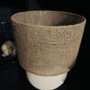 Textured brown lampshade on a cream base against a dark background