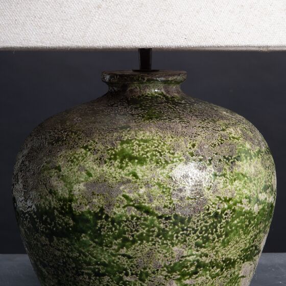 Green ceramic vase with textured surface on a dark background