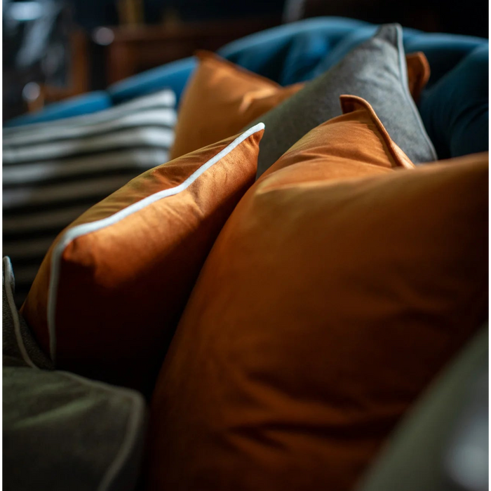 Close-up of orange and gray pillows on a sofa with blurred background