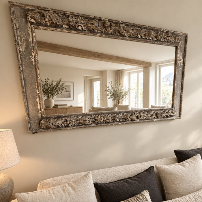 Distressed ornate rectangular mirror on cream living room wall above sofa with cushions