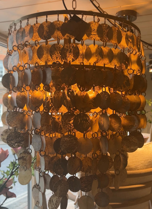 Decorative chandelier with rows of hanging marble circular pendants in a warm indoor setting