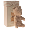 Teddy bear with a bow tie in front of a striped box labelled 'My First Teddy'.