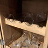 Clear glass bottles and glasses on wooden shelves.