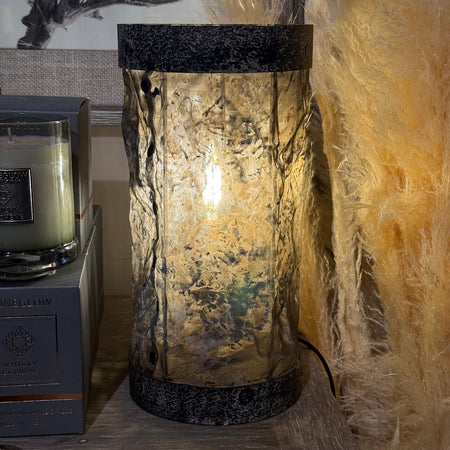 Decorative lamp with textured metal and parchment style fabric shade in a room setting
