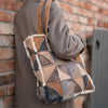 Person carrying a sheepskin patchwork shopping bag against a brick wall.