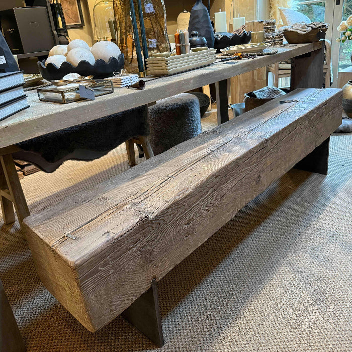 Wooden dining bench in a room with decorative items and furniture.