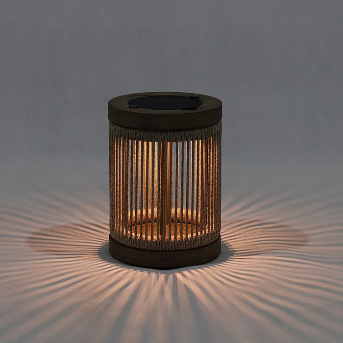 Cylindrical outdoor solar light with rope design casting soft light on a grey background