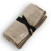 Beige linen tablecloth tied with black ribbon and frayed edge design with Lovely Linen brand label on white background