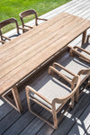 Gommaire Sally teak dining armchairs at rectangular teak dining table on decked area with lawn behind