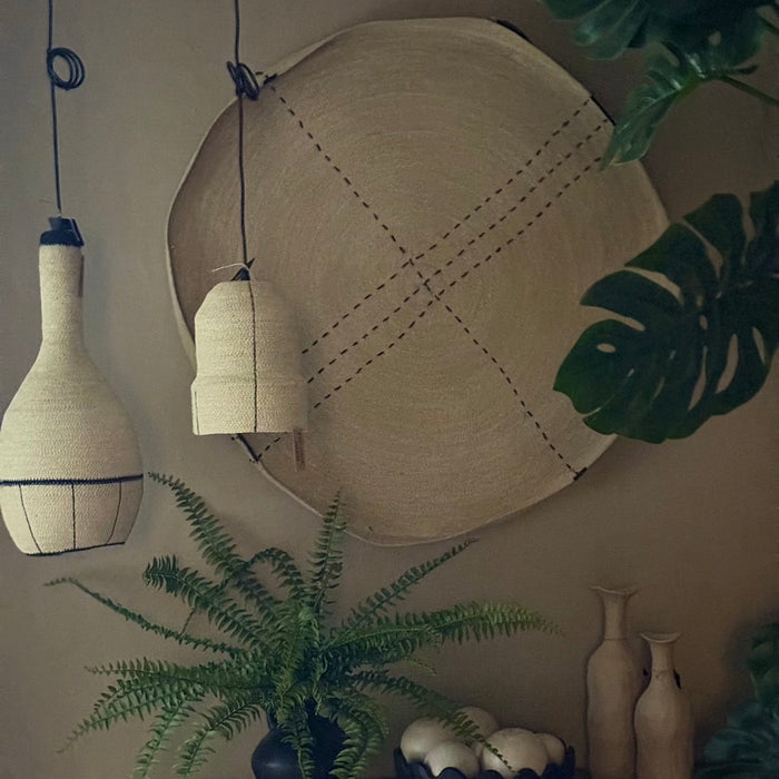 Seagrass Wall art tray above console with green fern in pot, vases and ornaments and seagrass hanging lights in living room