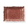 A rectangular ceramic appetizer plate with a floral old pink glaze and intricate detailing along the edges.