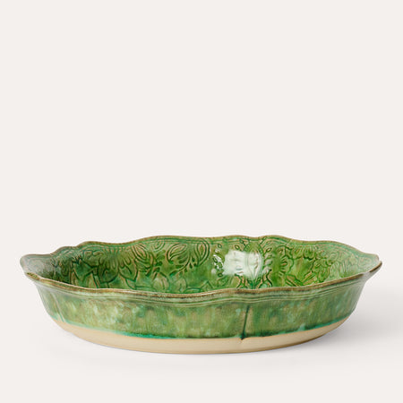 A round ceramic pie dish with a green seaweed pattern on the inside.