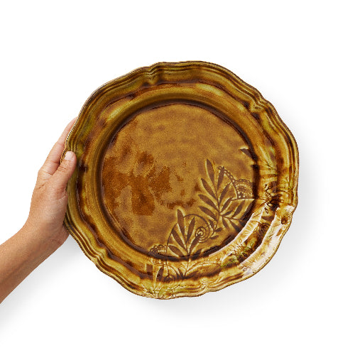 Hand holding pineapple brown coloured glazed dinner plate with leaf design