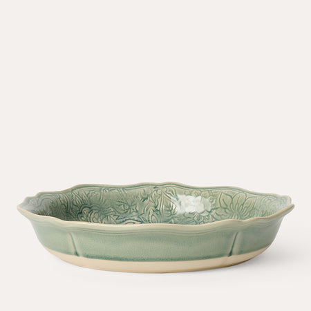 A green ceramic pie dish with a floral pattern on the bottom, crafted from durable white stoneware clay.
