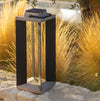 Solar-powered outdoor lamp on a stone surface with grass and trees in the background