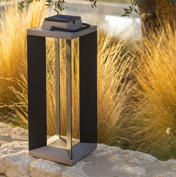 Solar-powered outdoor lamp on a stone surface with grass and trees in the background